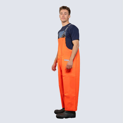 Salopette nautica Ocean® Mariner arancione impermeabile con bretelle, vista laterale, indossata con stivali neri